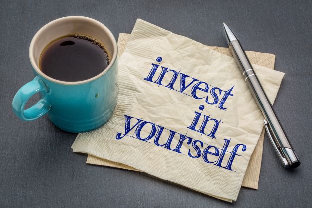 Manifestation, Part 1-coffee mug and sign saying, "invest in yourself".